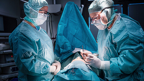 Ästhetische Chirurgie: Chirurgen führen eine Augenlidoperation in einem sterilen OP-Saal durch.